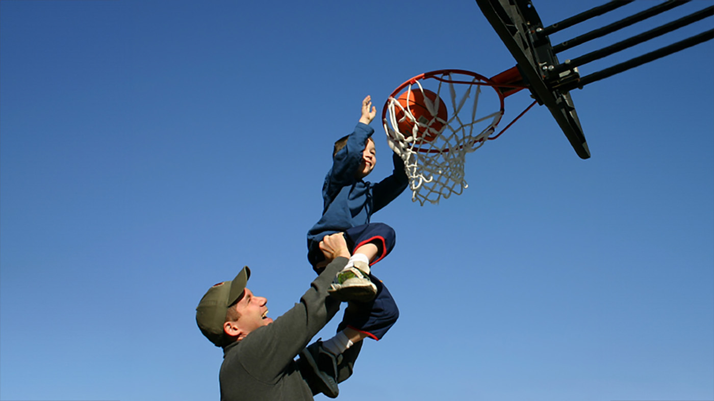 Child and adult playing basketball